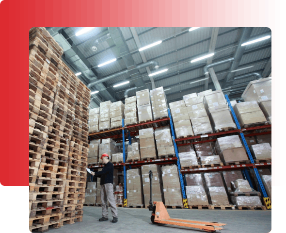 A man standing in front of stacks of pallets.