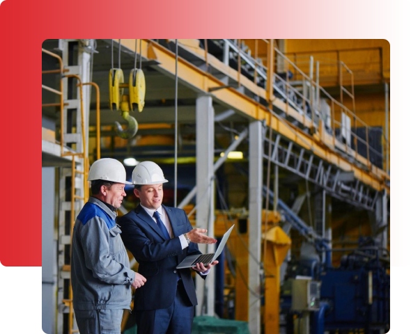 Two men in suits and hard hats are standing next to a building.